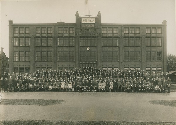 Deze foto is genomen ter gelegenheid van het 35 jarig jubileum in 1927. Het voltallige personeel poseert trots voor de gevel van hun werkplek.