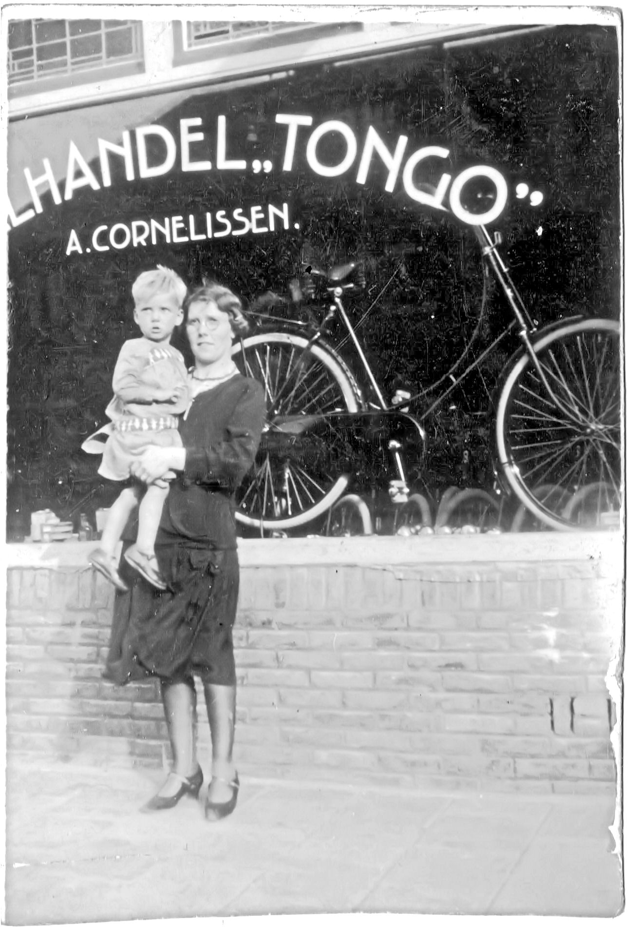 Foto van mijn oma met mijn vader op de arm voor de fietsenwinkel +/- 1932